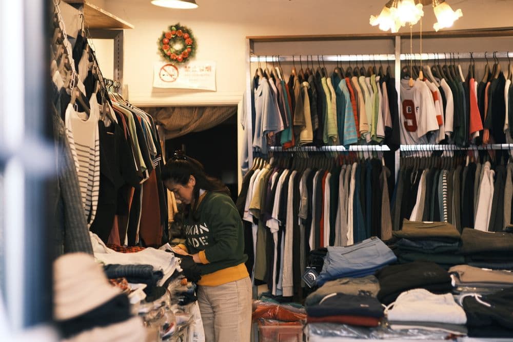 Lojista organizando roupas nas araras da loja